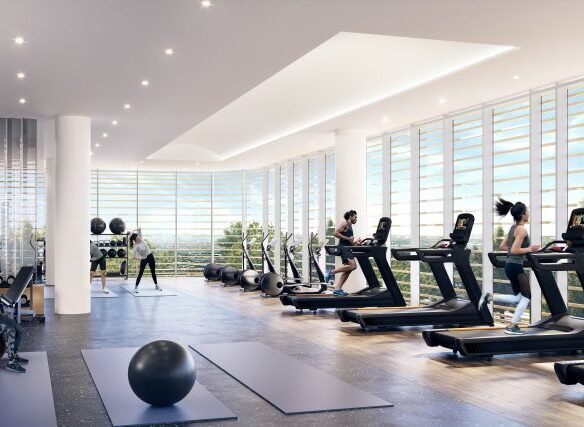 A modern gym at Park Place, with large windows and natural light. People are using treadmills and exercising on yoga mats. Exercise balls and fitness equipment are visible in this spacious, clean space, perfectly complementing the contemporary vibe of VMC Condos.