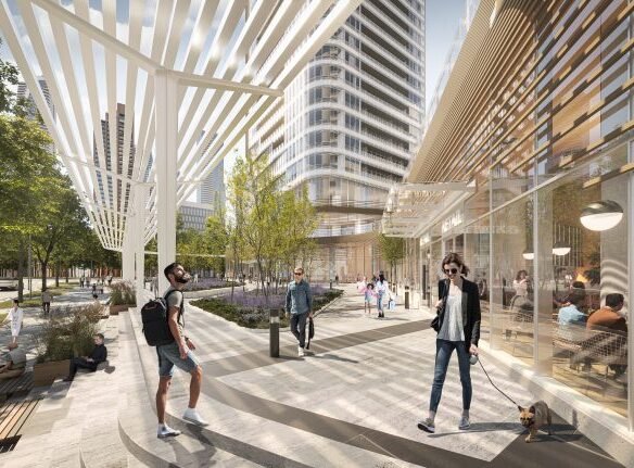 A modern urban streetscape with people walking on a sunlit plaza. High-rise buildings, including Park Place VMC Condos, and a canopy structure provide shade. Trees line the sidewalk as individuals sit, stroll, and interact in this lively, open space.