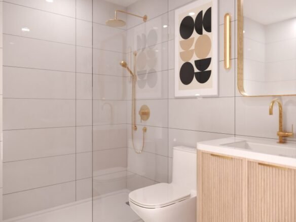 A modern bathroom in VMC Condos features light gray tiles, a gold showerhead, and a matching faucet. A framed abstract artwork adorns the wall, while a mirrored cabinet sits above the wooden vanity. The marble-patterned floor adds elegance to this Park Place residence.