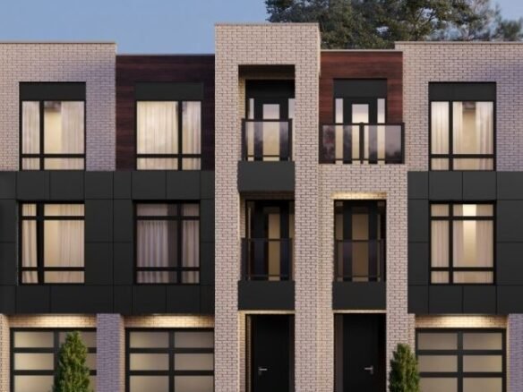 Nestled in the charming Ravine Towns, this modern three-story building with a flat roof showcases large windows and dark panels against light brickwork. Two entrances invite you in, flanked by small shrubs. A clear sky and partial trees complete the picturesque setting.