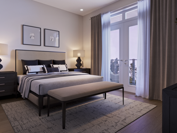 A cozy bedroom in new homes features a double bed with a gray and white striped duvet, flanked by two bedside tables with matching lamps. A bench sits at the foot of the bed, while framed art hangs above. Soft light pours through a large window with curtains, adding to the room's charm.