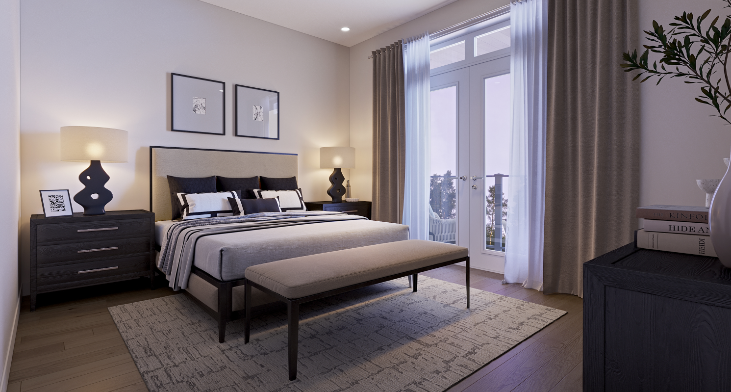 A cozy bedroom in new homes features a double bed with a gray and white striped duvet, flanked by two bedside tables with matching lamps. A bench sits at the foot of the bed, while framed art hangs above. Soft light pours through a large window with curtains, adding to the room's charm.
