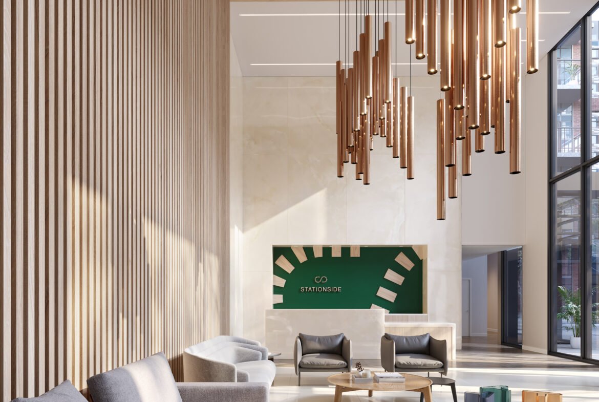 A modern lobby with wood paneling features a large hanging light fixture, gray couches, and a round wooden coffee table. A green sign with white graphics is on the far wall, and large windows flood the space with natural light—echoing the elegance of new condos in Brampton.