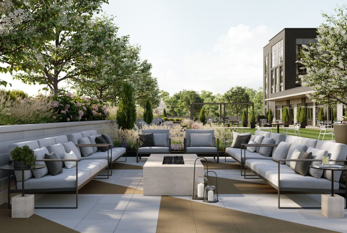 A modern outdoor patio features sleek gray sofas encircling a central rectangular stone fire pit. Adorned with potted plants and lanterns, this serene setting is enriched by the backdrop of trees and a contemporary building, ideal for new homes in Toronto.
