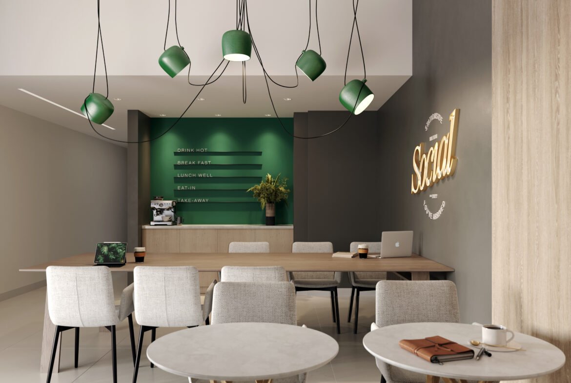 A modern cafe interior with round marble tables and light gray chairs. A green counter with menu items is at the back, beneath pendant lights. "Social" glows on the wall. A cup of coffee and laptop sit on one table, offering a cozy space to discuss new homes in Toronto or pre-construction homes nearby.