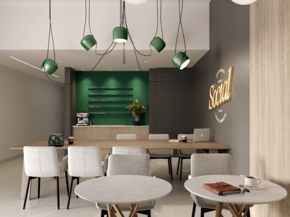 A modern cafe interior with round marble tables and light gray chairs. A green counter with menu items is at the back, beneath pendant lights. "Social" glows on the wall. A cup of coffee and laptop sit on one table, offering a cozy space to discuss new homes in Toronto or pre-construction homes nearby.