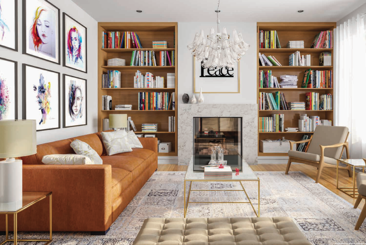 A stylish living room in one of the new homes features a brown leather sofa, two beige chairs, a glass coffee table, and a tufted ottoman. Bookshelves flank the fireplace, and framed artwork decorates the white walls. A chandelier hangs from the ceiling as large windows illuminate the space.