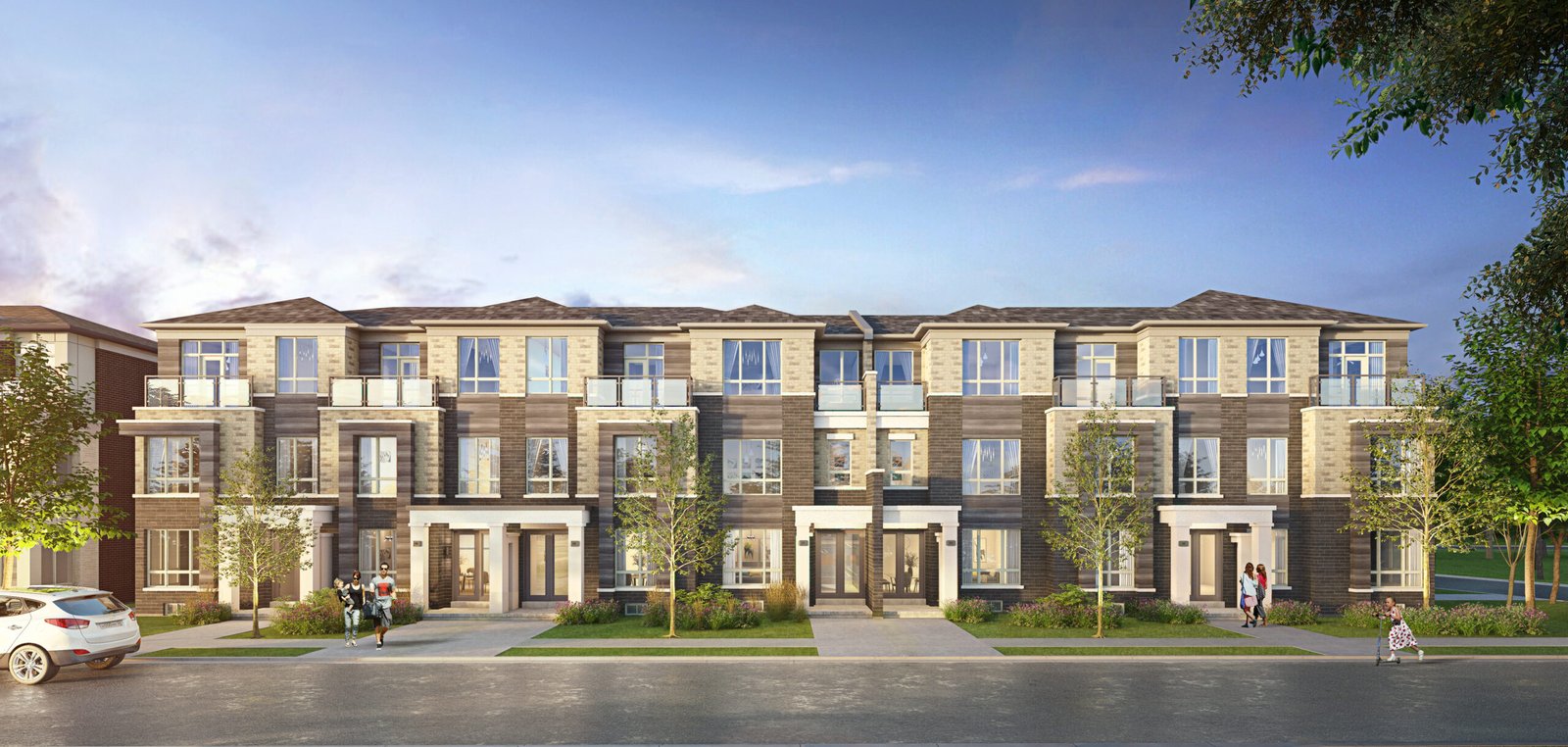 A modern row of three-story townhouses with large windows and balconies, set against a blue sky. The facade features brick and light stone accents. Trees and grass line the sidewalk, with a few people and a parked car visible. Perfect for those seeking new homes in Brampton.