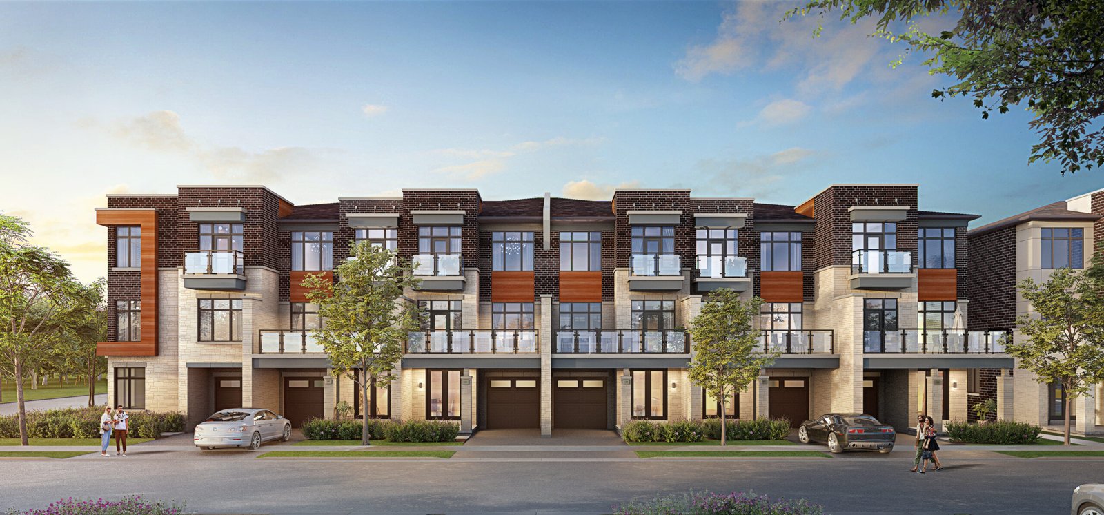 A modern three-story townhouse complex with large windows and balconies features a mix of stone and wood accents. Three cars are parked in front, and a few trees line the street under a clear blue sky. Discover pre-construction homes that offer style and comfort in this picturesque setting.