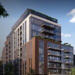 A modern multi-story building with large glass windows and balconies is surrounded by trees under a clear blue sky, creating a contemporary urban setting. Perfect for those interested in new condos in the GTA, this architecture promises stylish living amidst nature.