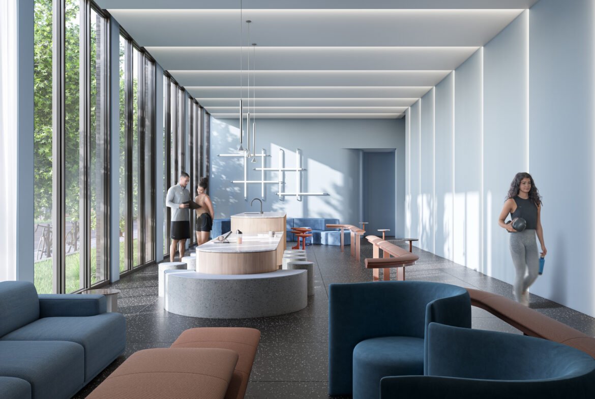 A modern, sunlit lounge in Above Condos boasts large windows and blue and brown seating. It features a long table with minimalist decor. Two people stand at a counter, while another walks by holding a drink. Lush greenery enhances the real estate appeal just outside the windows.