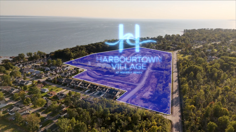 Aerial view of a coastal area with trees and houses. A translucent blue overlay highlights "Harbourtown Village at Waverly Beach," revealing new condos near the shoreline. The ocean shimmers in the background, inviting potential homeowners to explore this picturesque setting by SG Homes.