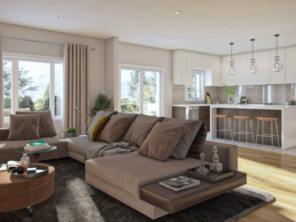 A modern, open-plan living room and kitchen in Sienna Woods. Features a large beige sectional sofa with brown pillows, a round coffee table, and a kitchen island with bar stools. Sunlight streams through large windows, highlighting the wooden floors and the charm of this tranquil town.