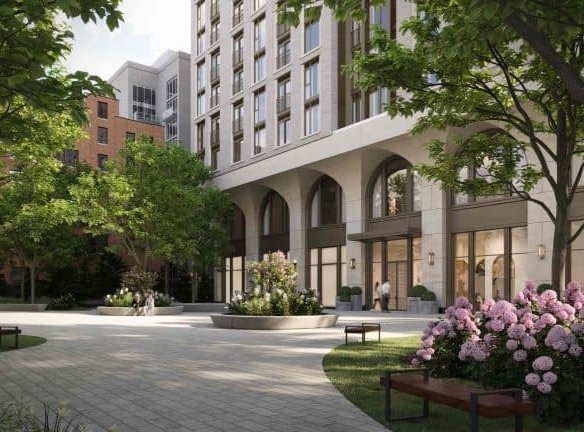 The 101 Spadina Condos boast a modern apartment building with arched entrances, surrounded by lush greenery. A paved walkway in the foreground is flanked by flower beds of pink hydrangeas and benches, while trees provide shade, creating a serene, inviting atmosphere.