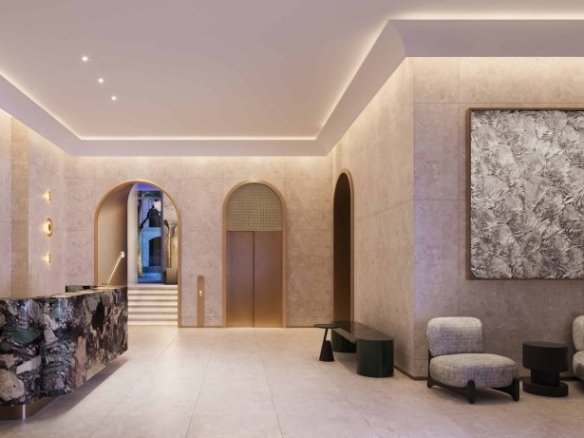 A modern lobby at 101 Spadina Condos featuring a marble reception desk on the left and two cushioned chairs with small black tables on the right. The space is softly lit with recessed lighting and adorned with minimalist decor, including large abstract wall art.