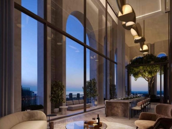 A luxurious, modern lounge at 101 Spadina Condos with floor-to-ceiling windows showcasing a cityscape at dusk. The room features elegant, curved sofas, a glass coffee table with a wine bottle and glasses, plants, and a sleek, suspended light fixture. Large arches frame the windows.