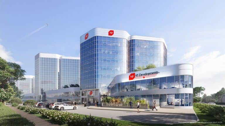 A modern office building with a reflective glass facade, labeled "NF Developments," stands amidst lush greenery and a bustling parking lot. It mirrors the ambitions of SG Homes in pre-construction projects. Above, a clear blue sky and distant airplane trail complete the scene.