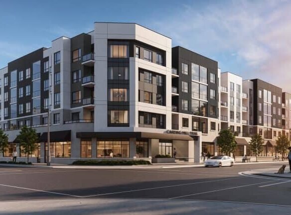 Modern five-story apartment building with a mix of black, white, and gray exterior panels. Large windows and ground-floor retail spaces enhance the appeal of these new homes in GTA. The setting includes a few cars and trees, all under a clear sky at sunset.