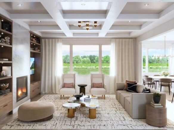 A modern living room in the Clarehaven estates with a coffered ceiling, large windows, and a view of a lush green landscape. The room features a light-colored L-shaped sofa, two armchairs, a fireplace, built-in shelves, and a round ottoman. A dining area is visible through a wide doorway.