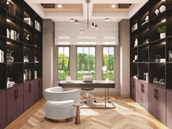 Modern home office with large windows revealing a lush green view. The room features built-in dark wood bookshelves, a contemporary desk with a sleek chair, and a stylish, curved white lounge chair with a small side table on a herringbone-patterned floor—true Clarehaven Estates elegance.