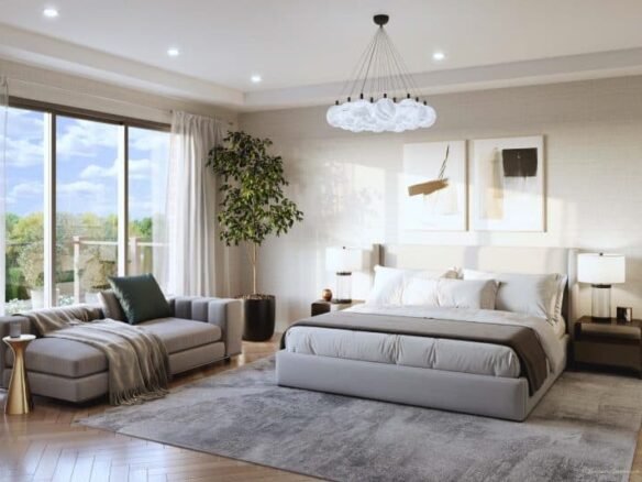 Modern bedroom at Clarehaven Estates with a large bed, light gray headboard, and neutral bedding. To the left is a comfortable sofa draped with a green blanket. A large window offers views of trees and lets in natural light. A chandelier hangs above, and there is a potted plant in the corner.