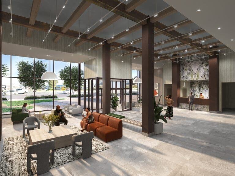 The spacious lobby of the new condos features large windows, multiple seating areas, and contemporary decor. People sit and stand engaged in conversation near a reception desk on the right. Large pendant lamps hang from the ceiling, highlighting a vibrant introduction to modern living spaces.