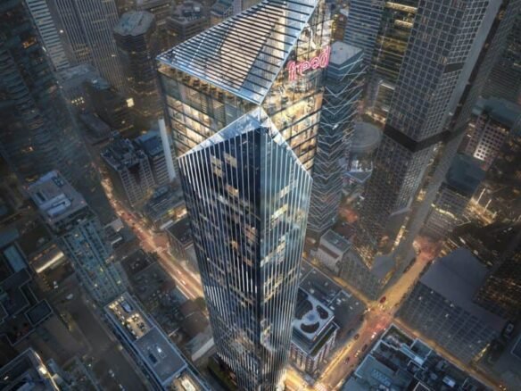 Aerial view of a modern cityscape featuring a tall, geometric skyscraper with a distinct angular design. The building is illuminated against the backdrop of neighboring high-rises and city streets lined with vehicles. Near the top, the sign reading "Freed Hotel" is visible among sleek residences.