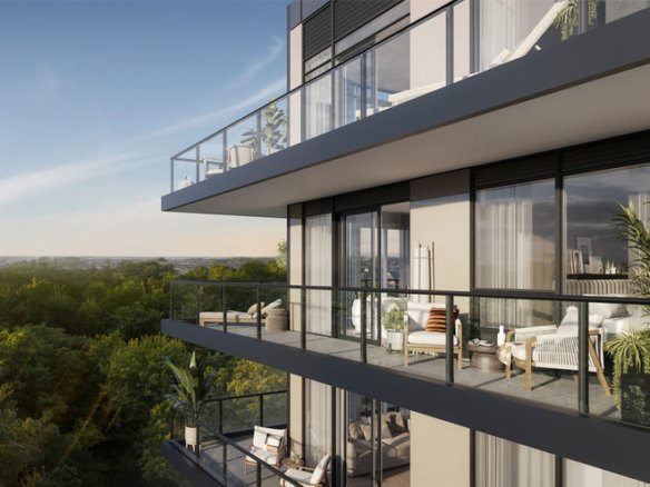 A modern condo building with multiple glass-walled balconies, each furnished with outdoor seating and plants. The structure overlooks a lush green forest under a clear sky. The sun is setting or rising, casting a warm glow over the scene, reminiscent of the serene views along the High Line.