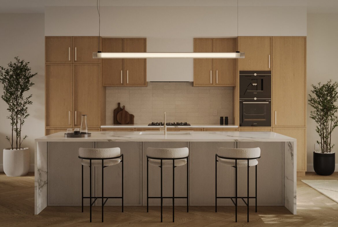 The modern kitchen in new homes in GTA features light wood cabinets, a marble island with three cushioned bar stools, a sleek hanging light fixture, two potted plants, and built-in stainless steel appliances. The room is warmly lit and elegantly organized.