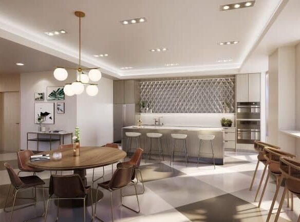 A modern kitchen and dining area in new GTA condos features a round wooden table, chairs, and bar stools around a large island. The room showcases geometric wall patterns, hanging lamps, artwork, and large windows ushering in natural light.