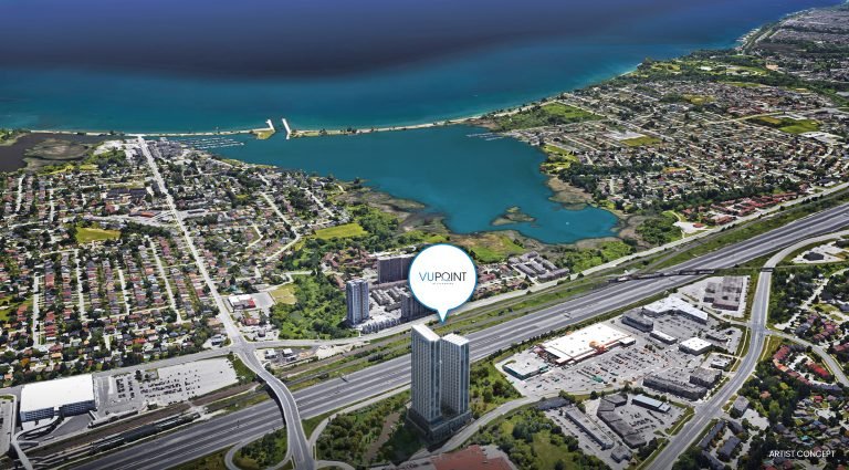 Aerial view of a coastal cityscape reveals "VIP POINT," a tall building near the highway. The mix of residential and commercial areas hints at new homes in GTA, with pre-construction homes promising a vibrant future against the backdrop of a vast shimmering body of water.