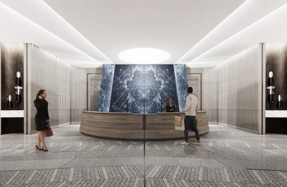 A modern hotel lobby features a circular reception desk with two people engaged in conversation. In the background, a large marble wall mirrors the elegance found in pre-construction homes. The floor is a patterned mix of tiles, and soft lighting illuminates the space.