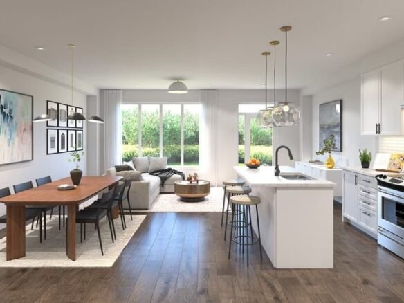 Modern open-concept living and dining area in new condos with hardwood floors. Features a wooden dining table, black chairs, island kitchen with white cabinets, gray sofa, coffee table, and large windows offering a garden view. Artwork and pendant lights enhance the decor.