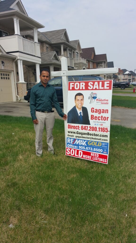 A man standing next to a for sale sign.