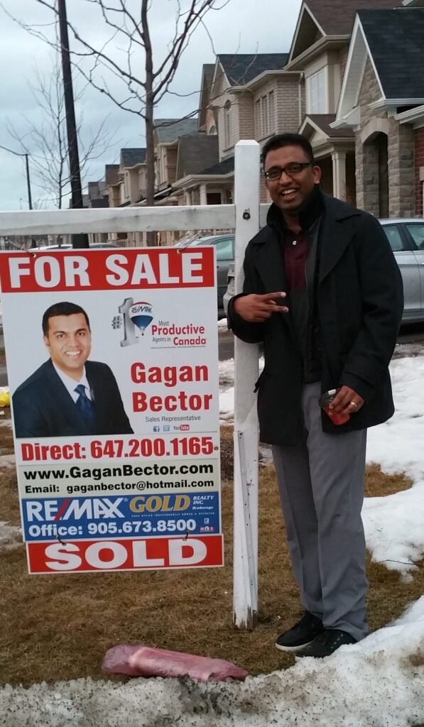 A man standing in front of a for sale sign.