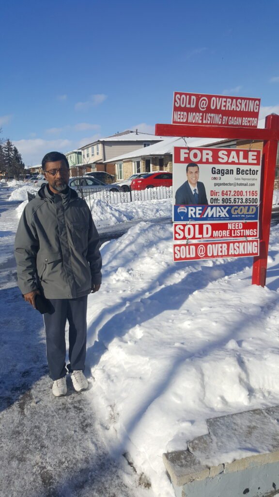 A man standing next to a real estate sign.