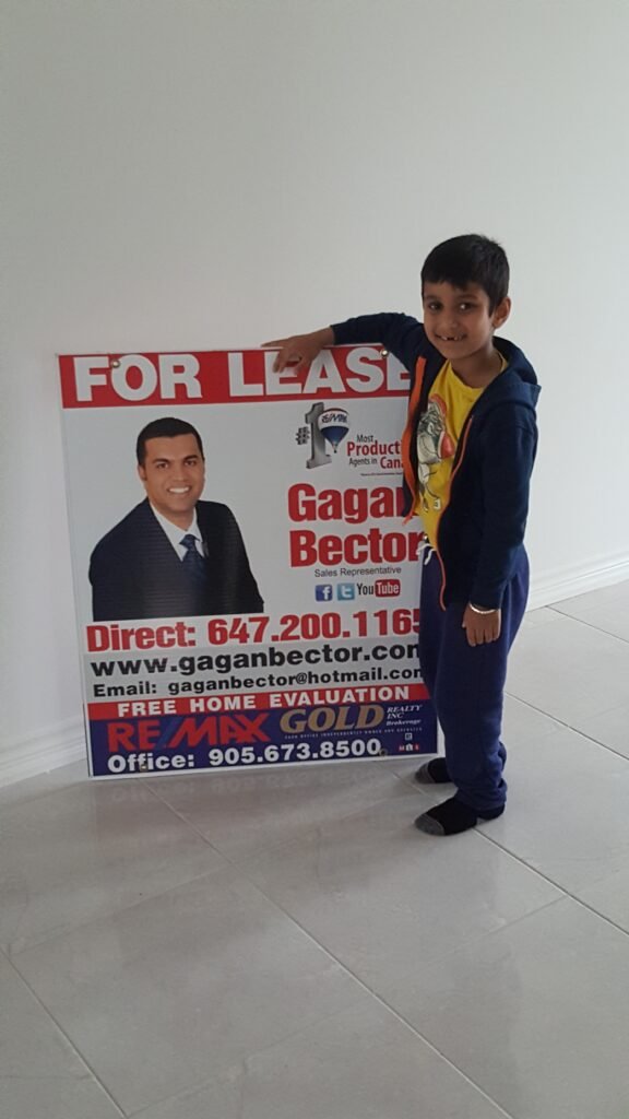 A young boy standing next to a for lease sign.