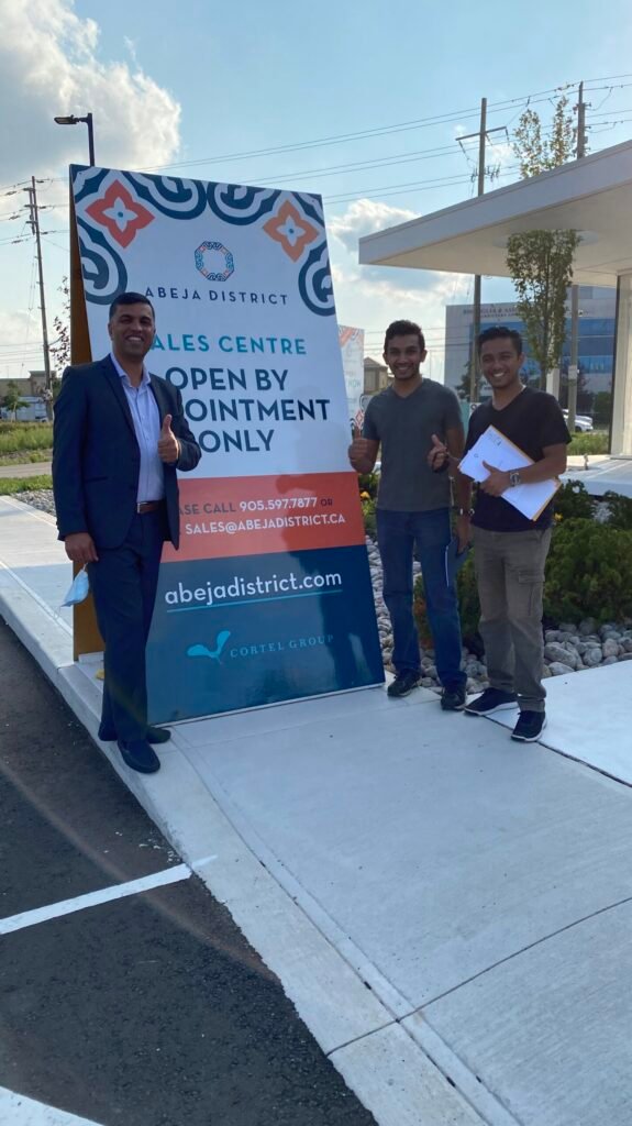 Three men standing in front of a building with a sign.