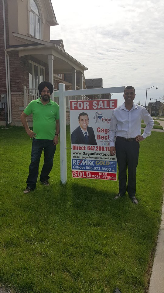 Two men standing in front of a for sale sign.