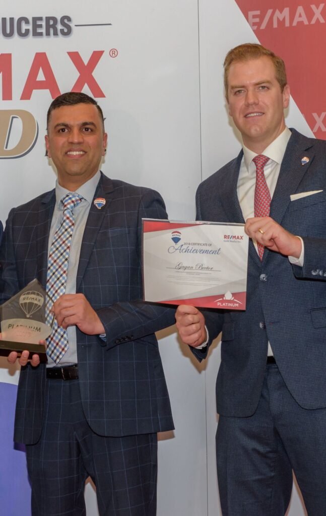 Three men in suits holding a remax gold award.