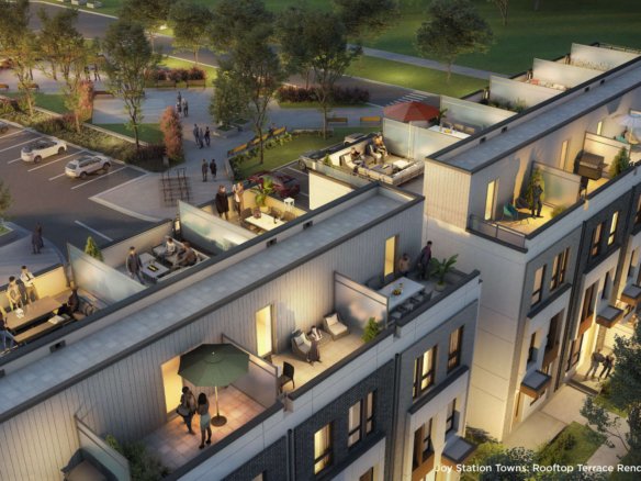 A rooftop terrace rendering of Joy Station Towns depicts modern townhouses with outdoor seating areas, tables, greenery, and people socializing. In the background, a parking area and trees create a lush environment. The scene is set during dusk, with warm lighting enhancing the inviting atmosphere.