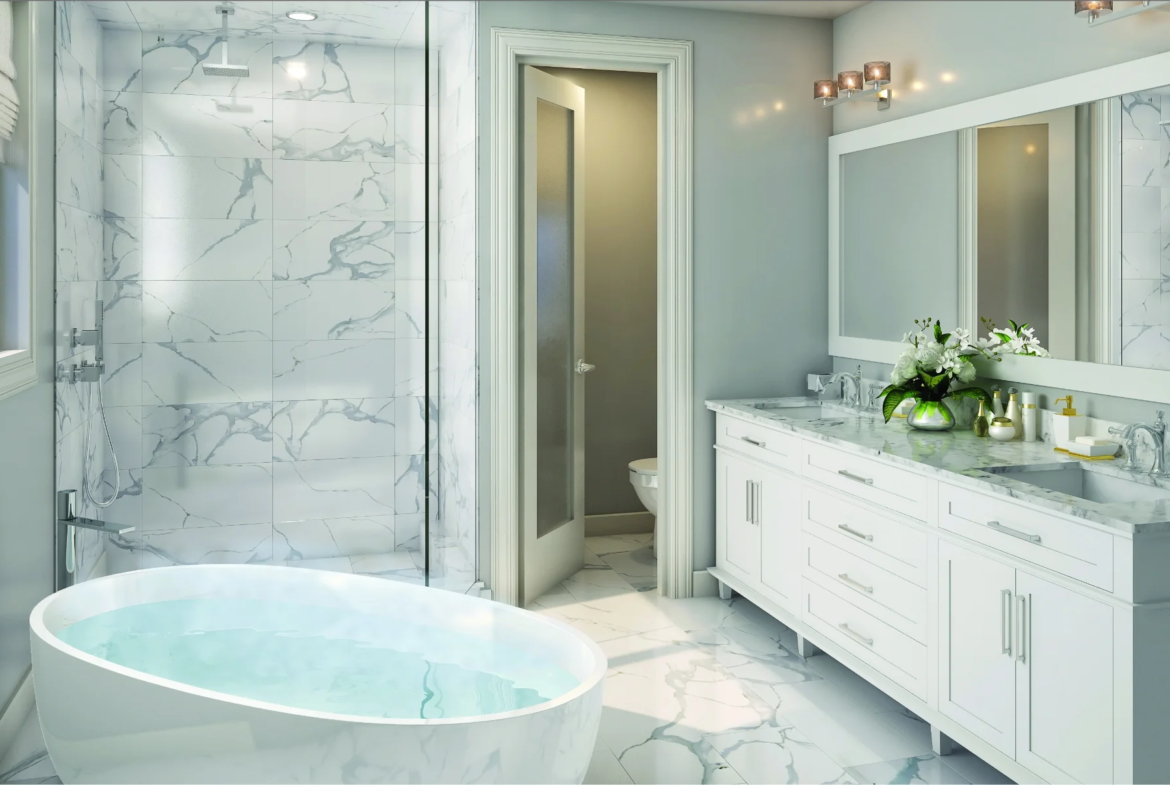 Modern Caledon Club bathroom featuring a freestanding tub filled with water, marble floors and walls, large mirror above double sink vanity, glass shower, and a door to the toilet area. White and light gray tones with stylish lighting complete the look.