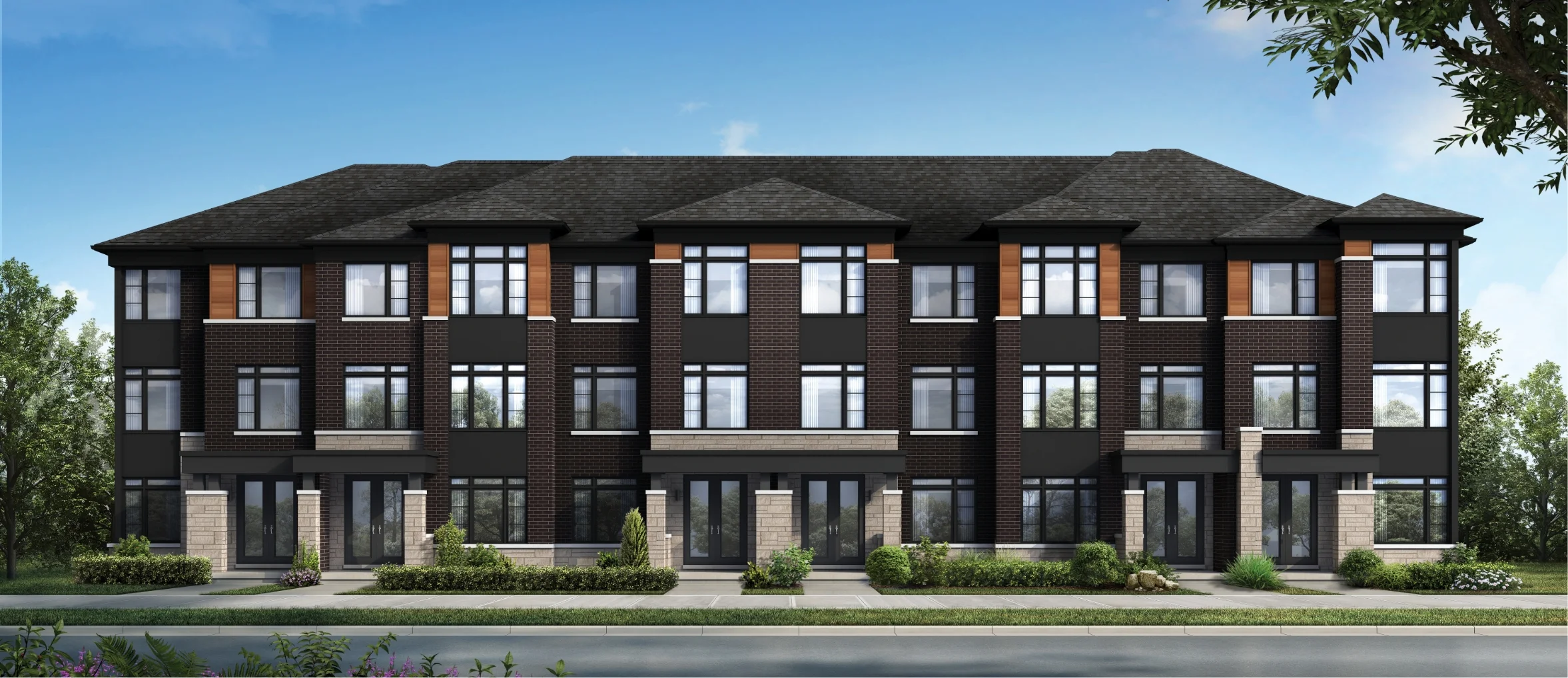 Modern three-story townhouse complex at Caledon Club with dark brick exterior, large windows, and landscaped greenery in front, set against a clear blue sky.