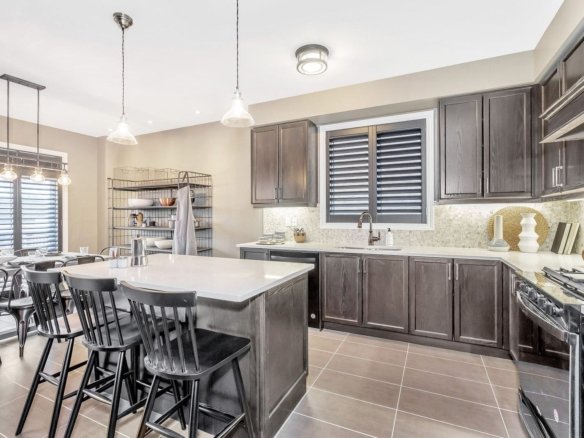 Modern kitchen and adjoining family dining area in the Enchant model home at Empire Legacy